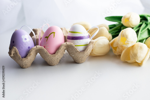 Easter eggs in a package with flowers and tassels on a white background