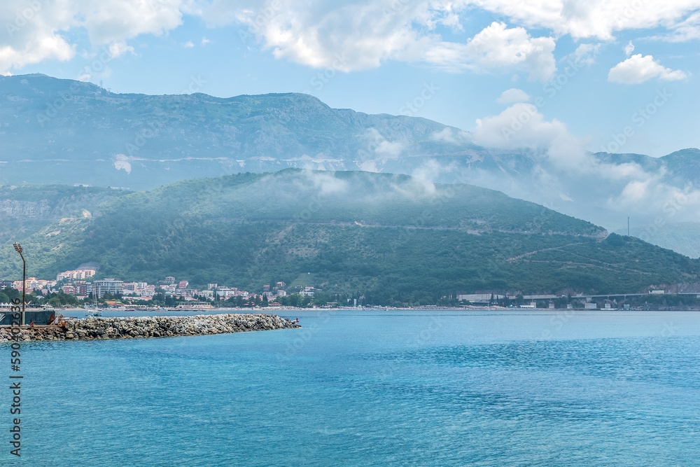 Budva Riviera in the morning, Montenegro. View from the Adriatic Sea to the city coastline and mountains in fog and clouds on the horizon