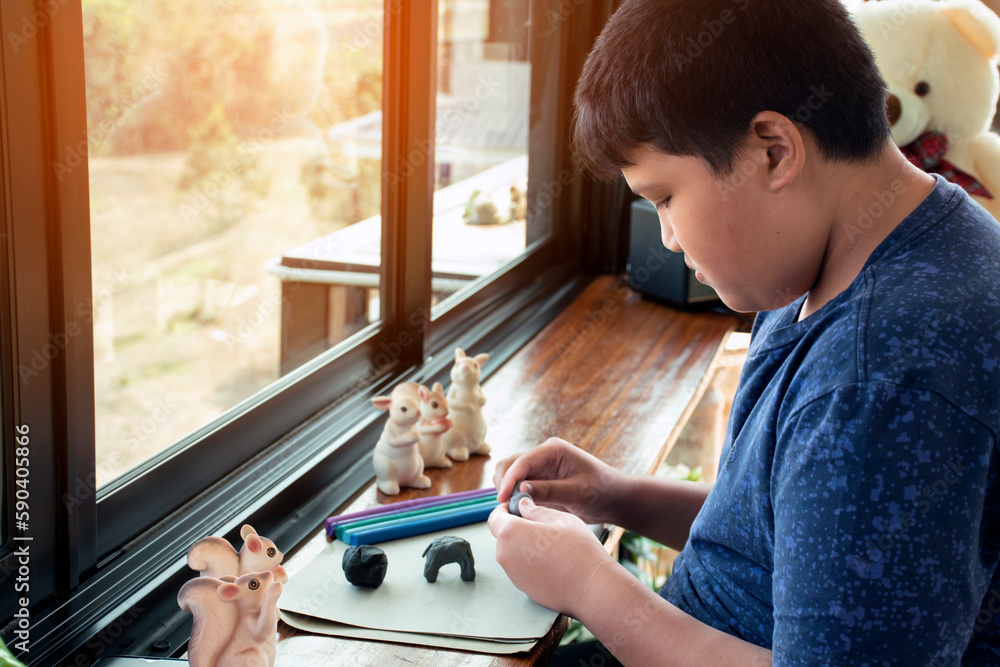 An autistic boy molding different shapes of colored plasticine prepared