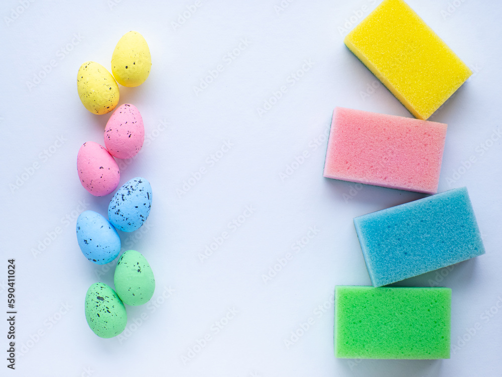 Happy Easter and cleaning concept. Easter eggs and colorful sponges on white background with copy space. Easter greating card. Top view, flat lay. Cleaning stuff and colorful eggs. Housekeeping. Happy Easter and cleaning concept. Easter eggs and colorful sponges on white background with copy space. Easter greating card. Top view, flat lay. Cleaning stuff and colorful eggs. Housekeeping.
