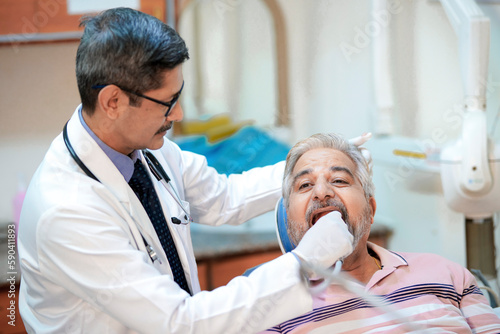 Dentist checking senior patient teeth at clinic