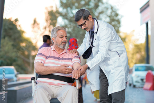 Tableau sur toile Doctor checking to old man while he is moaning in pain.