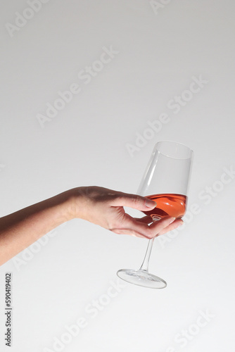 A hand holding a glass with rose wine