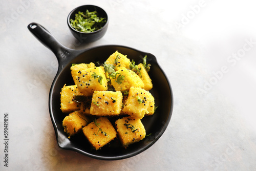 Indian chana Dal dhokla. Khaman dhokla is a famous dish of Gujarat. Made using rice, a healthy mix lentils and pulses, along with spices. garnished with coriander and fried chilies. Copy space photo