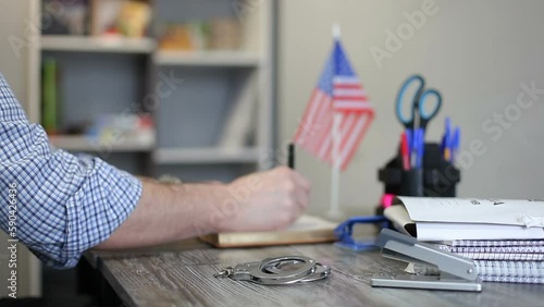 Police station in America. The police officer writes down the data, takes the handcuffs from the table and turns off the lights in the office. photo