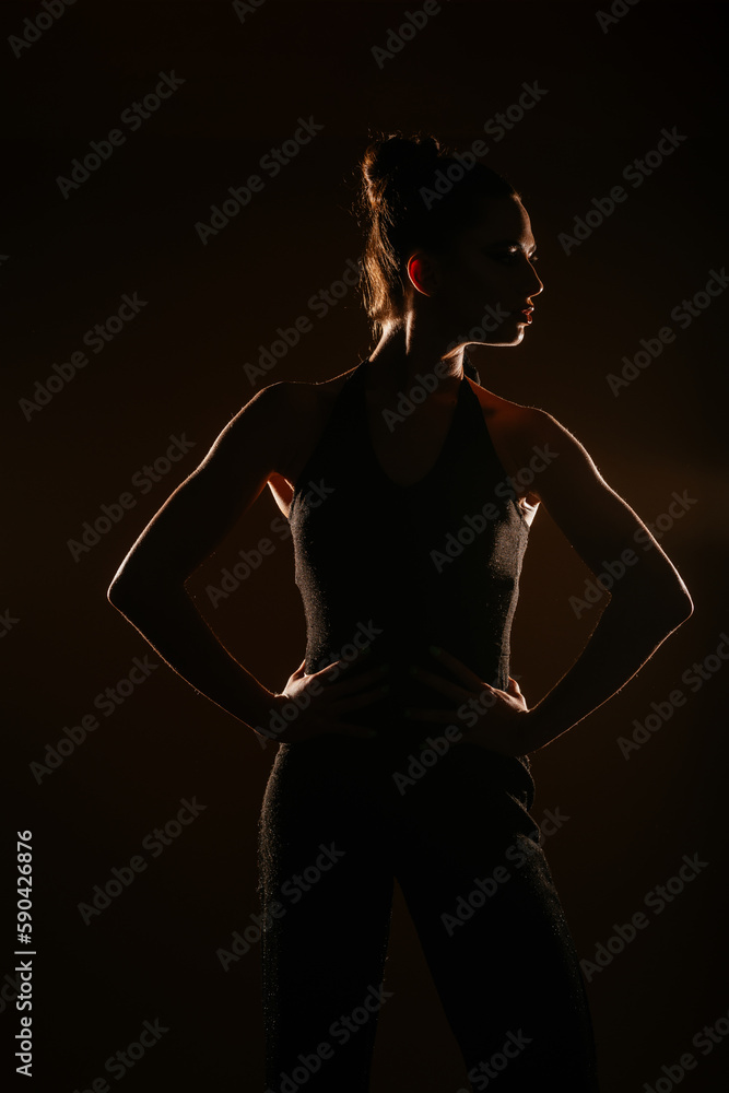 Silhouette girl posing with her hands on the spine