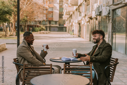 Two young multiracial business people having fun conversation while taking their first morning coffee