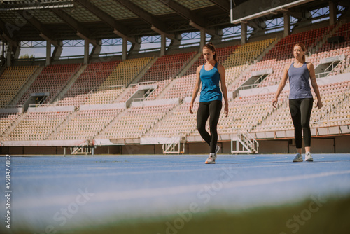 Sporty female friends walking on a blue sports track