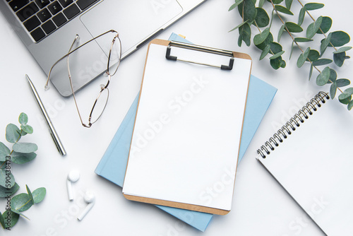 Modern white office desk table with laptop, notebook and other supplies. photo