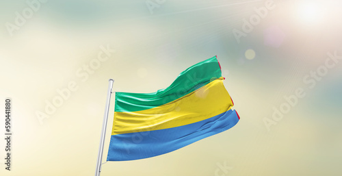 Waving Flag of Gabon on blur sky. The symbol of the state on wavy cotton fabric.