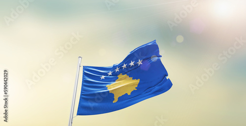 Waving Flag of Kosovo on blur sky. The symbol of the state on wavy cotton fabric.