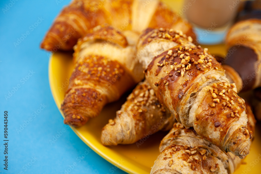 Chocolate croissants or croissant with nut crumbs on a plate. Delicious breakfast on the table. Tasty sweet baking dessert for coffee. Food background. Fresh buttery croissants rolls