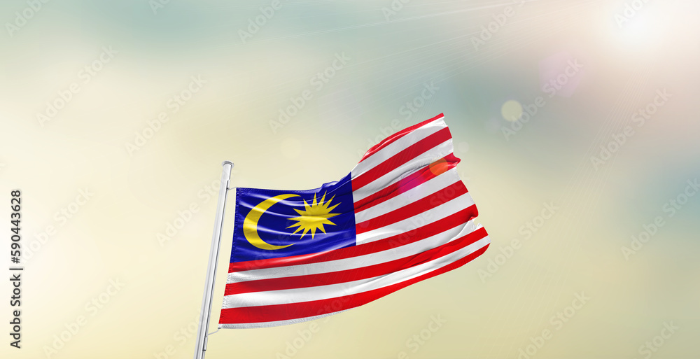 Waving Flag of Malaysia on blur sky. The symbol of the state on wavy cotton fabric.