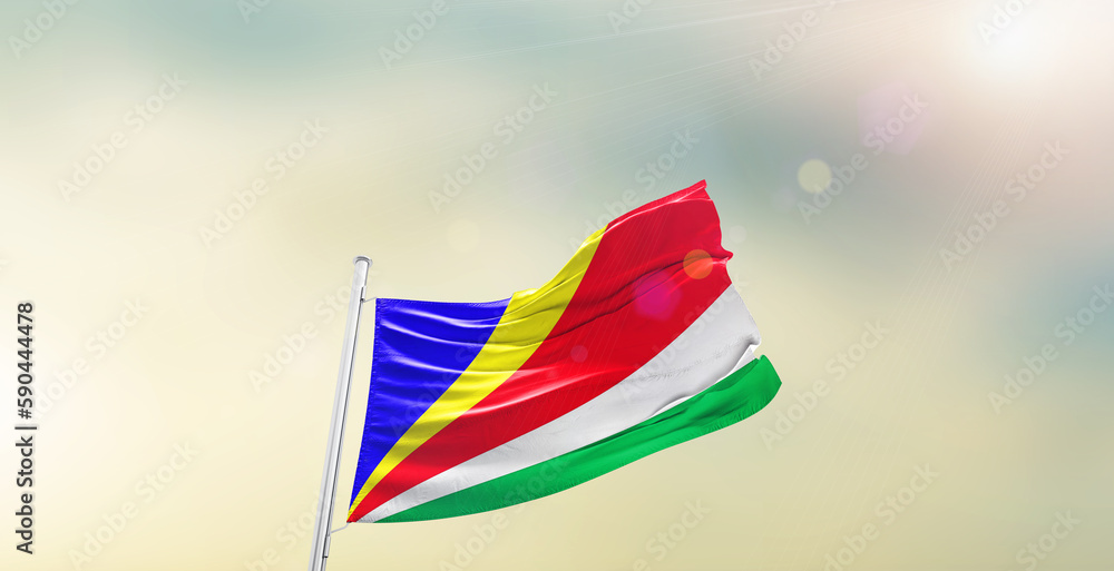 Waving Flag of Seychelles on blur sky. The symbol of the state on wavy cotton fabric.