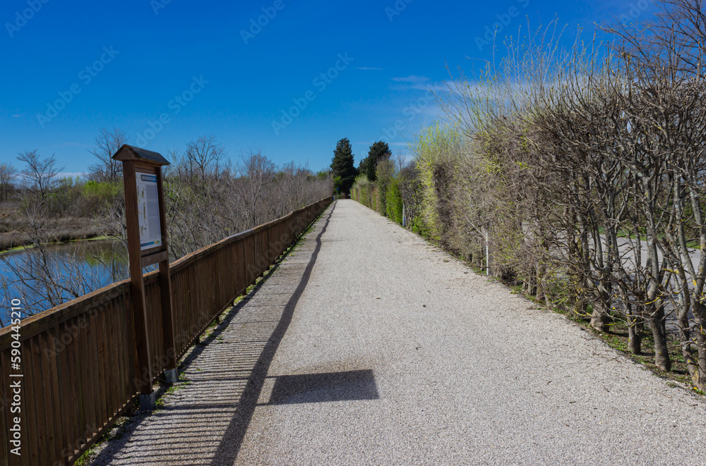 Grado cycle path near Valle Cavanata. Grado lagoon. White road with a fence near the water. April 1, 2023, Grado, Italy