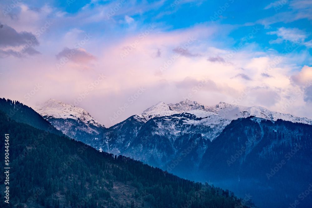 monsoon clouds moving over snow covered himalaya mountains with the blue orange sunset sunrise light over kullu manali valley