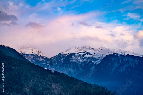 monsoon clouds moving over snow covered himalaya mountains with the blue orange sunset sunrise light over kullu manali valley © Memories Over Mocha