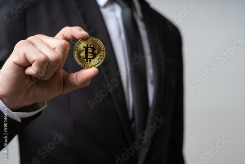 Business man wearing business suit showing golden Bitcoin cryptocurrency on white background and copy space. Bitcoin is future financial as virtual digital money on internet online blockchain system.