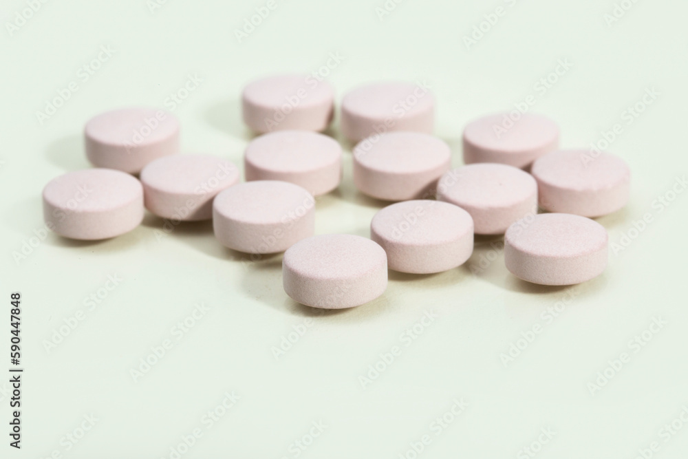 Close up shots of medicine tablets and capsules on white background. White and colored tablets placed in a group.