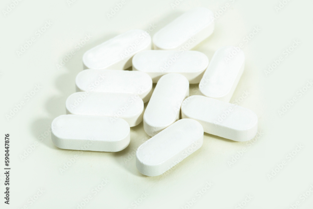 Close up shots of medicine tablets and capsules on white background. White and colored tablets placed in a group.