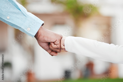 Adult, child and hands in fist bump for trust, agreement or partnership in generations against a blurred background. Big and small hand bumping fists for support, collaboration or teamwork and growth