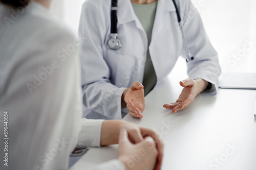 Doctor and patient discussing current health examination while sitting at the desk in clinic office, closeup. Perfect medical service and medicine concept © rogerphoto