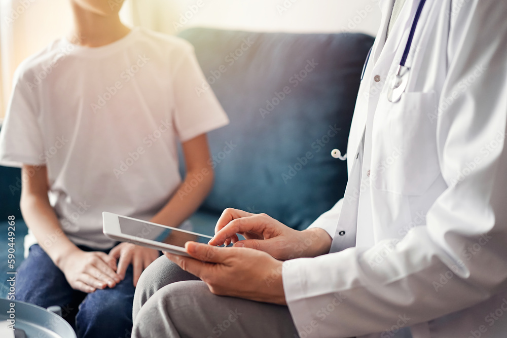 Doctor woman and kid boy patient at home. The pediatrician using tablet computer while filling up medical records, close up. Medicine, healthcare concepts Doctor woman and kid boy patient at home. The pediatrician using tablet computer while filling up medical records, close up. Medicine, healthcare concepts