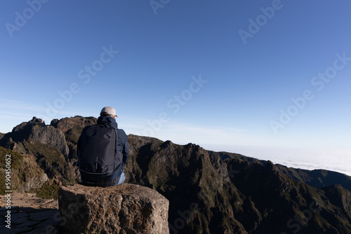 Tourist sits at mountain top against the background of majestic mountains  Madeira  Portugal