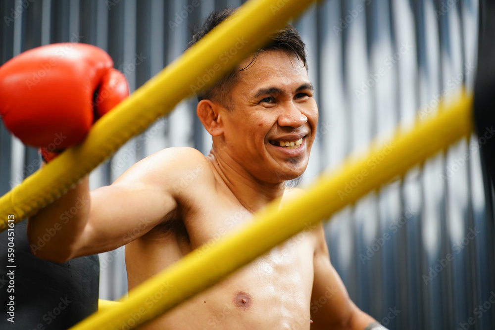 Fototapeta premium Muay Thai, The martial art of Thailand, Boxer sitting in the corner When the referee stops the fight in each round for the boxer to rest and the coach to introduce the fight in the next round.