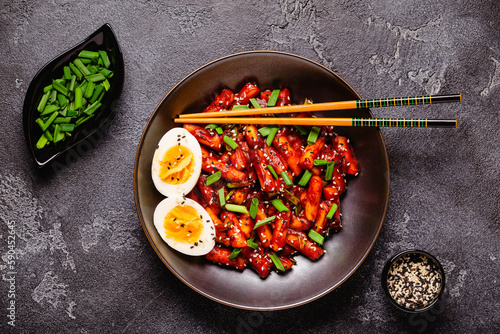 Tteokbokki, Teopokki fried rice cake in black bowl. photo