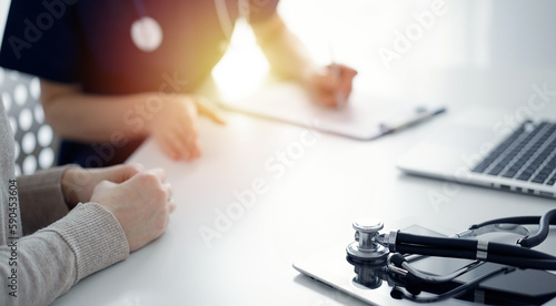 Stethoscope lying on the tablet computer in front of a doctor and patient at the background. Medicine, healthcare concept