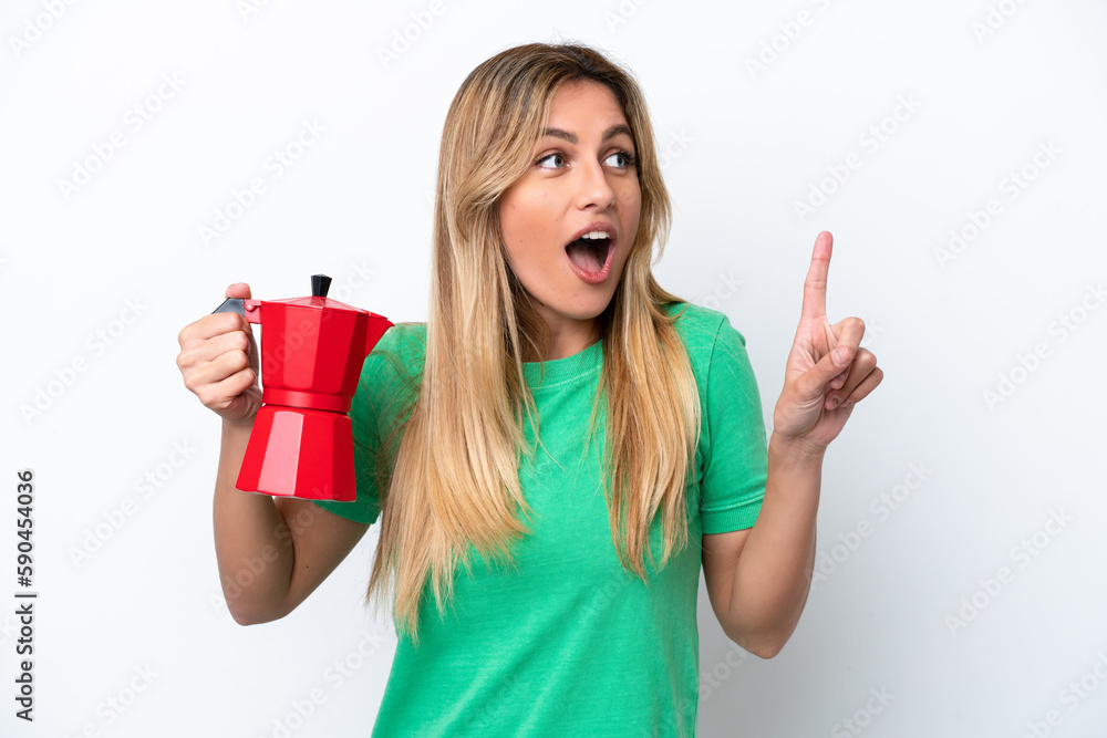 Young Uruguayan woman holding coffee pot isolated on white background intending to realizes the solution while lifting a finger up Young Uruguayan woman holding coffee pot isolated on white background intending to realizes the solution while lifting a finger up