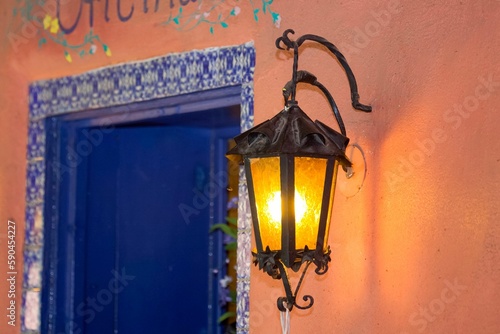 Closeup of illuminated light lantern next to a blue Spanish door