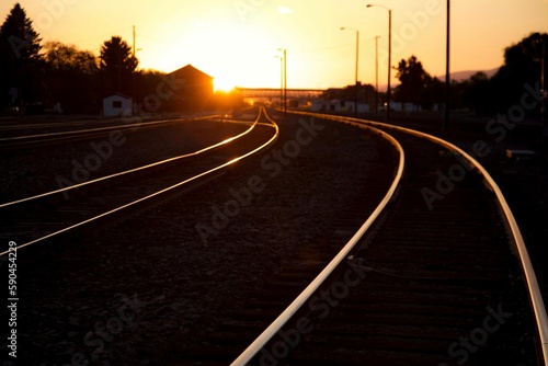 Empty railways with the golden sunset shining brightly in the background © Craig A Mccollum/Wirestock Creators