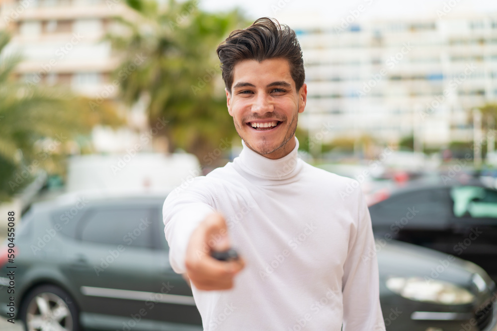 Fototapeta premium Young caucasian man at outdoors holding car keys with happy expression