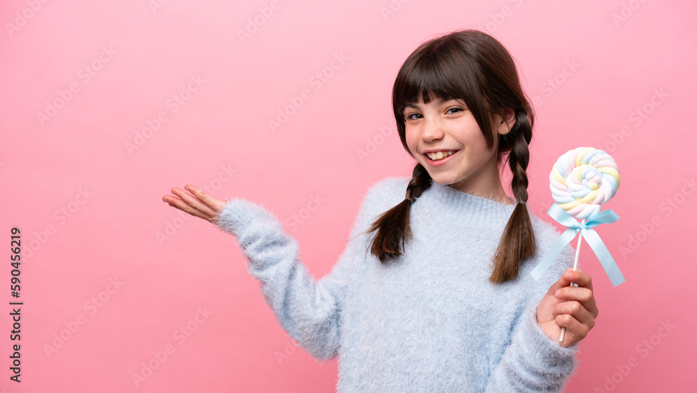 Little caucasian girl holding a lollipop extending hands to the side for inviting to come Little caucasian girl holding a lollipop extending hands to the side for inviting to come