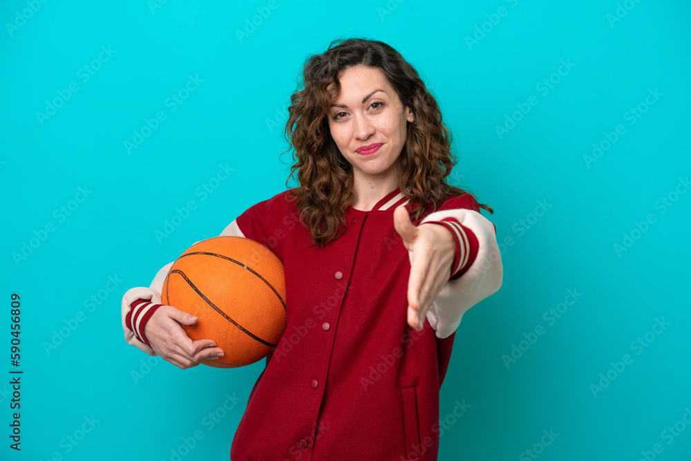 Young caucasian basketball player woman isolated on blue background shaking hands for closing a good deal