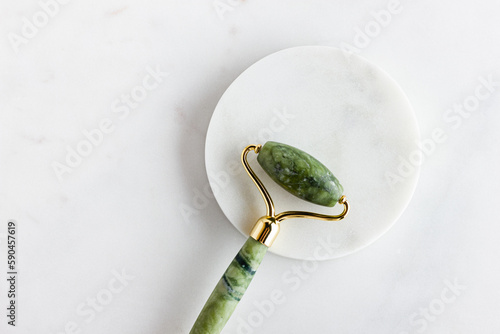 Fototapeta Naklejka Na Ścianę i Meble -  Green jade roller massager for face on white marble.