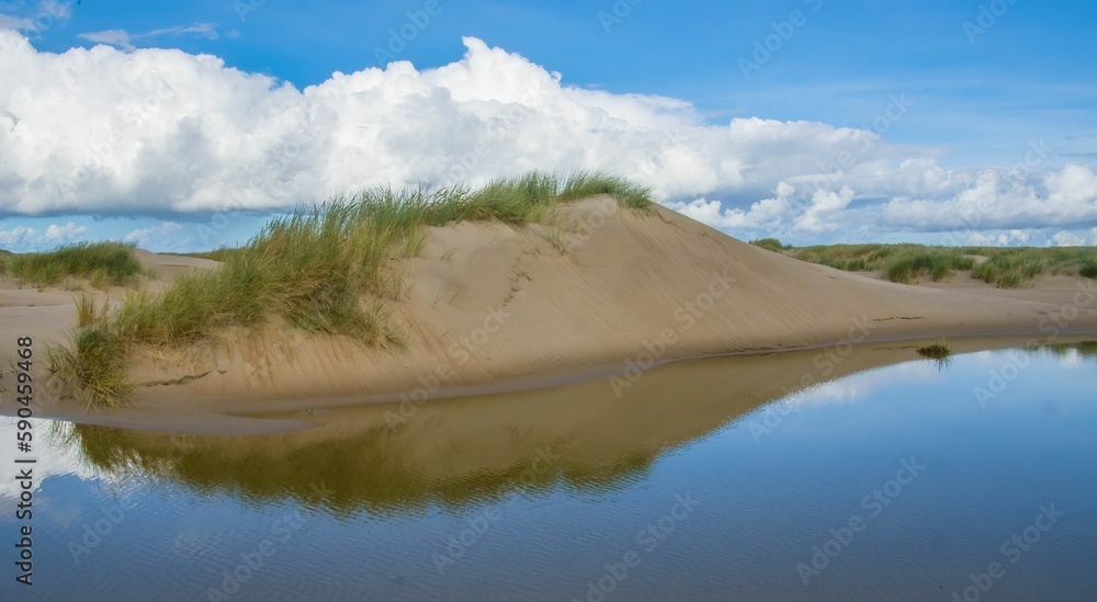Beautiful landscape of a river bank with sand dunes and grass