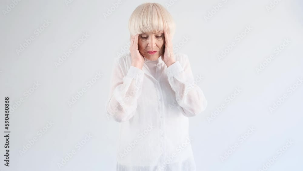 Portrait of an elderly woman suffering from a headache on a white background Portrait of an elderly woman suffering from a headache on a white background