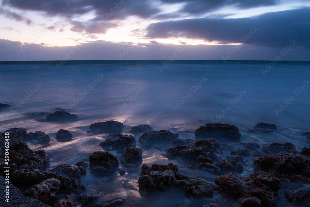Aerial view of sea waves breaking rocky beach during sunset Aerial view of sea waves breaking rocky beach during sunset