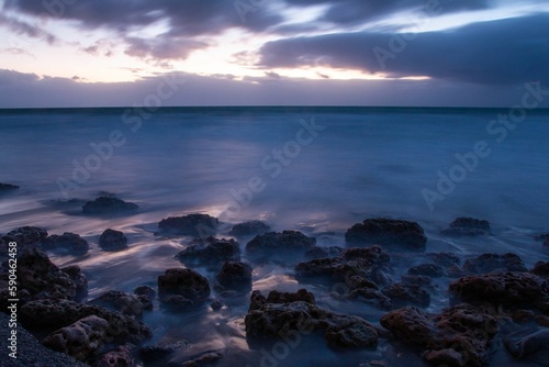 Aerial view of sea waves breaking rocky beach during sunset