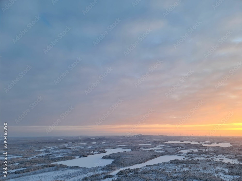 Scenic drone shot of sunset over lakes and snow-covered forests