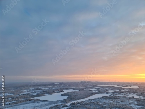 Scenic drone shot of sunset over lakes and snow-covered forests