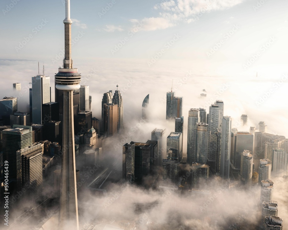 Obraz premium Aerial shot of the tower and other tall buildings covered with clouds, Toronto, Canada