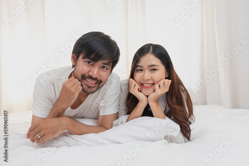Happy young asian couple embracing, teasing, playing cheerfully in bed at home, romantic time to enhance family bonding. family concept.