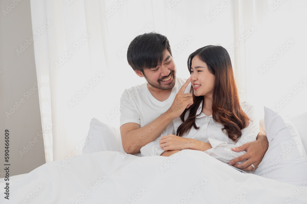 Happy young asian couple embracing, teasing, playing cheerfully in bed at home, romantic time to enhance family bonding. family concept.