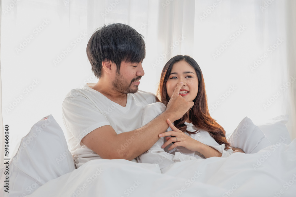 Happy young asian couple embracing, teasing, playing cheerfully in bed at home, romantic time to enhance family bonding. family concept. Happy young asian couple embracing, teasing, playing cheerfully in bed at home, romantic time to enhance family bonding. family concept.