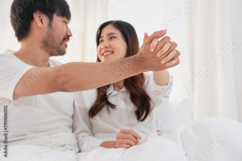 Happy young asian couple embracing, teasing, playing cheerfully in bed at home, romantic time to enhance family bonding. family concept.