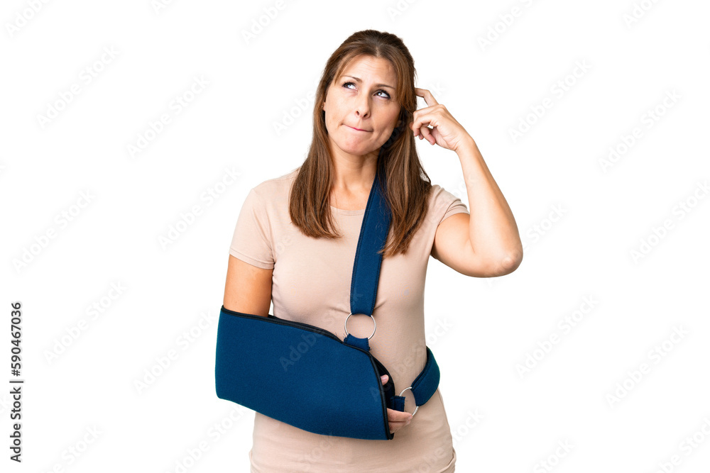 Middle age with broken arm and wearing a sling over isolated background having doubts and thinking Middle age with broken arm and wearing a sling over isolated background having doubts and thinking